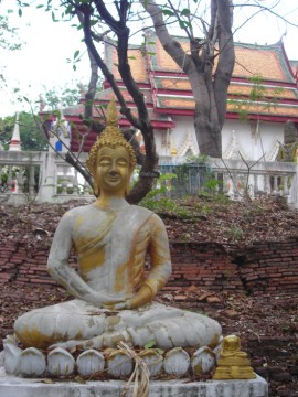 Buddha image in front of an old monastic structure